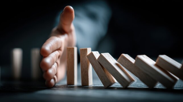 Business Hand Stops Cascading Dominoes with Preventing Crisis and Risk.