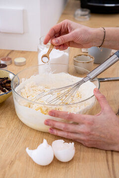 Home cooking. Kneading dough. Female chef hand adding measuring ingredient salt sugar in glass bowl with flour mixing whisk pastry mass.