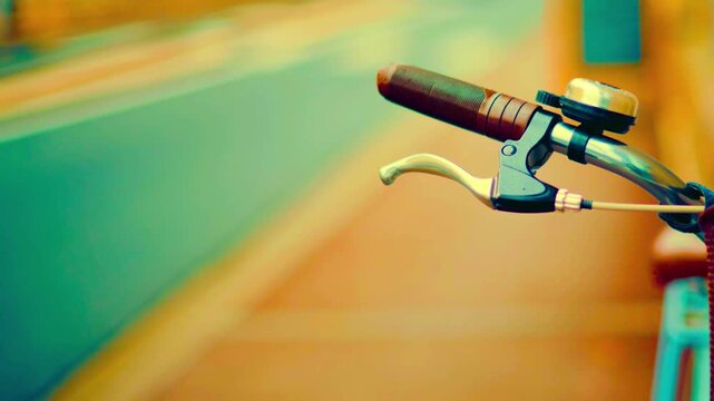 Bicycle handlebars with a bell and brake lever in motion on blurred background