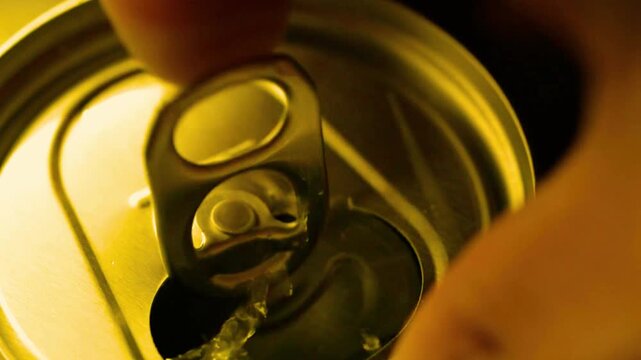 Finger opening metal beverage can tab in close up slow motion macro view