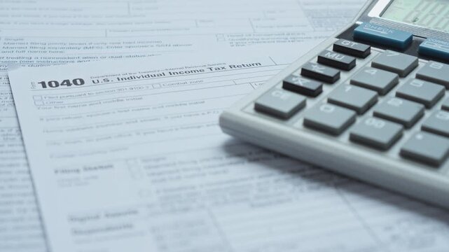 Calculator and pen rest on top of 1040 U.S. individual income tax return form