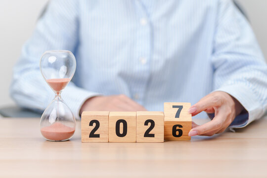 2026 end year to Happy New Year 2027 with hourglass on table. Resolution, time, plan, goal, motivation, reboot, countdown and New Year holiday concepts