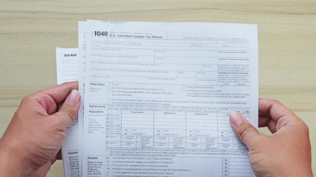 Person holds and organizes U.S. individual income tax return 1040 forms