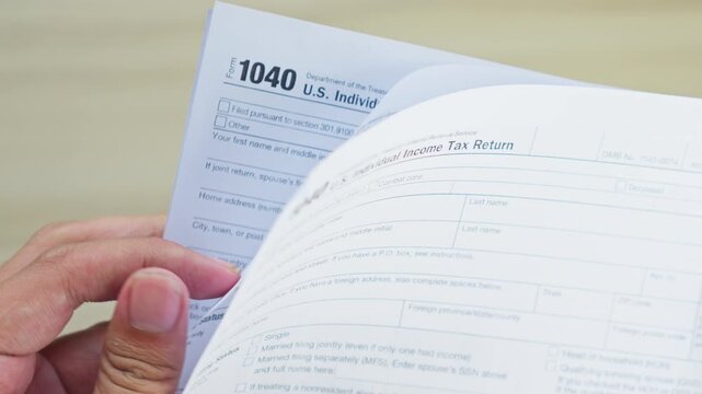 Person flips through U.S. individual income tax return 1040 pages