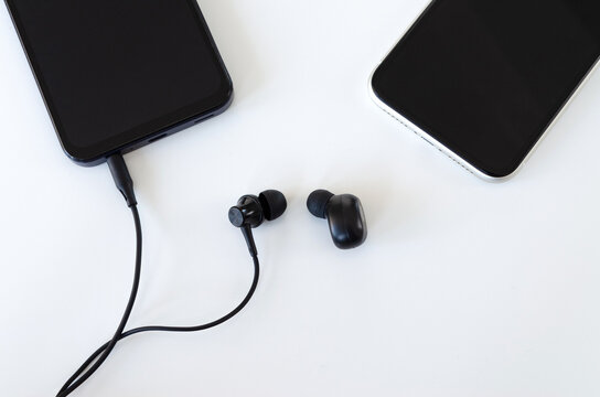 Auricular con cable y earbud inal&aacute;mbrico junto a tel&eacute;fonos m&oacute;viles