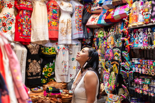 Latina Woman Admiring Colorful Mexican Embroidered Garments in Artisan Market