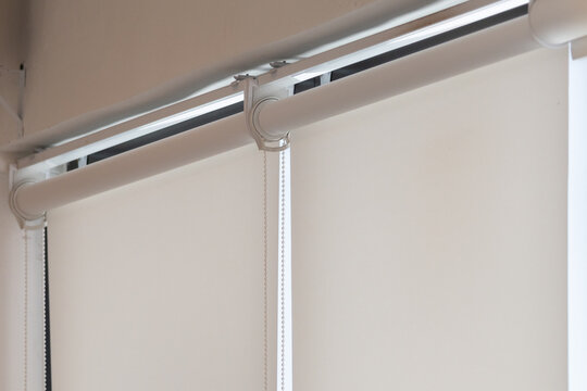 Close-up of beige roller blind with visible pull cord and metal rail