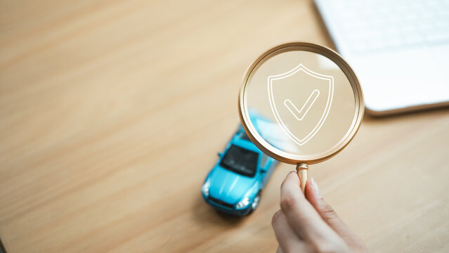 Car insurance concept with an agent reviewing vehicle protection through a magnifying glass and shield icon, symbolizing policy coverage and financial security.