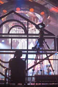 Backstage view of cameraman filming live event on stage under stadium lights with copy space