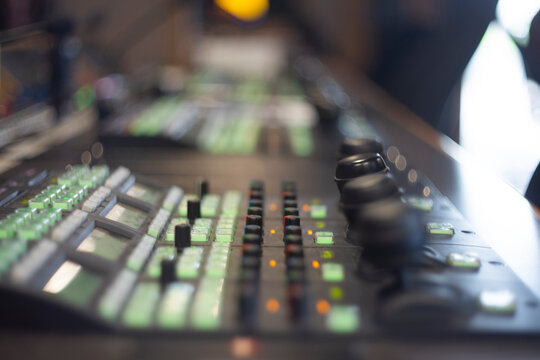 Professional video production switcher console with glowing green buttons and copy space