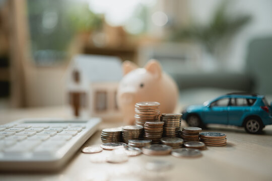 Savings for home and car ownership with coins, piggy bank, and calculator represent smart budgeting, financial planning, and future security.