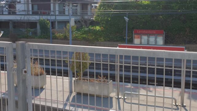 Larrabasterra train station platform with tracks and signs, showing urban public transport infrastructure and travel