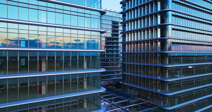 Modern glass office building complex with reflective facades, layered windows, and an open urban courtyard in clear daytime light.