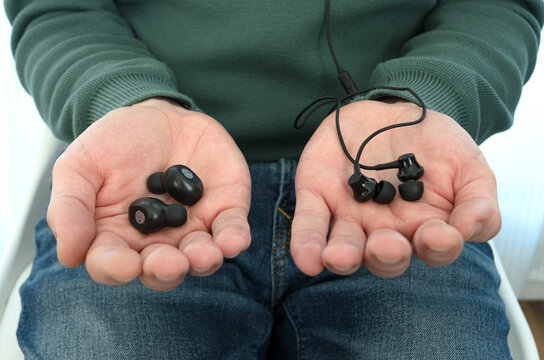 Persona comparando auriculares inal&aacute;mbricos y auriculares con cable