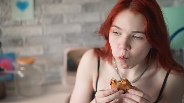Redhaired lady relishes crispy bites. Frecklefaced woman with energetic hair attentively consumes crispy snack. Gingerhaired woman eagerly devours crunchy morsel with focused enthusiasm