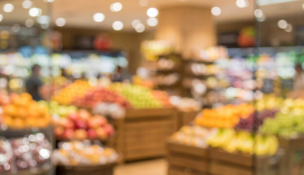 A blurred image of a grocery store showcasing colorful fruits and vegetables in well-organized displays, creating a vibrant shopping environment.
