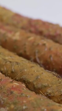Vertical Video: Extreme close-up shot of washing dirt off Chinese yam under running water.