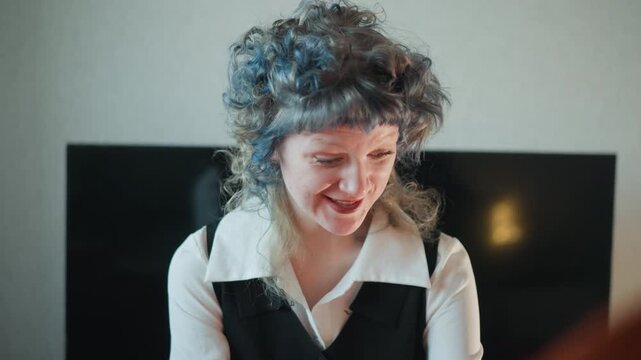 Caucasian woman seer laughing after reading, curly gray hair and bright smile light up cozy living room, playful energy and relief after prophetic insight, redheaded client blurred in foreground, warm