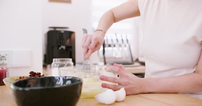 Bakery process. Whisking food. Woman chef hand stirring butter sugar egg ingredients for homemade dough in glass bowl on countertop.
