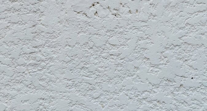 Close-up of a rustic white concrete wall with a highly textured, rough plaster surface.