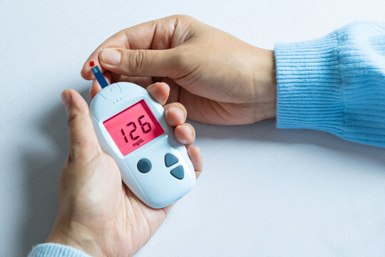 Woman's hands checking diabetes and hyperglycemia with digital blood sugar meter. Healthcare and medical concept	