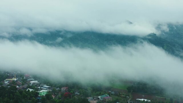 Aerial drone shot of mountain landscape covered by rolling mist and low clouds.