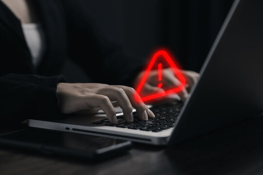 Cybersecurity warning concept with businesswoman typing on laptop, red alert symbol highlighting online threats, data breach risk, cyber attack, privacy, safety, and digital security.
