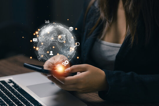 Businesswoman uses smartphone with virtual global network interface, representing digital transformation, worldwide communication, online business, technology, and global connectivity.
