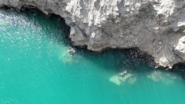 Turquoise lake and rocky shore in Xinjiang, top down drone view