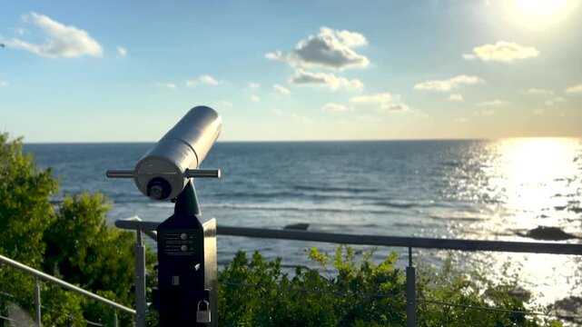 Sightseeing binoculars overlooking the sea at sunrise, panoramic ocean horizon view from an empty coastal observation deck, peaceful golden morning landscape. Scene E.