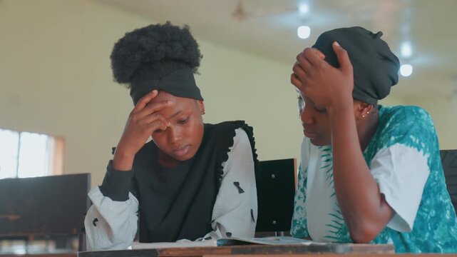 Mother offers gentle support and instruction to worried child in classroom. Caring mother patiently helps her distressed daughter understand difficult subject matter during study session