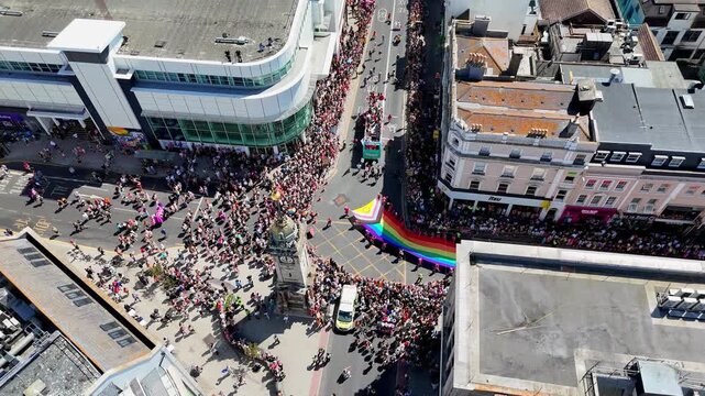 Large crowds gather as decorated floats and buses travel through the city during the annual Pride Community Parade.