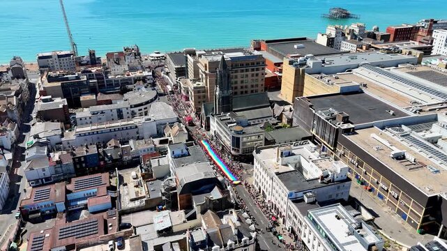 Aerial view of colourful floats and crowds taking part in the Brighton and Hove Pride LGBTQ Community Parade, themed The Power of Love.
