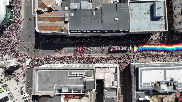 Parade participants, rainbow flags and vibrant floats fill the streets during the Brighton and Hove Pride celebrations.