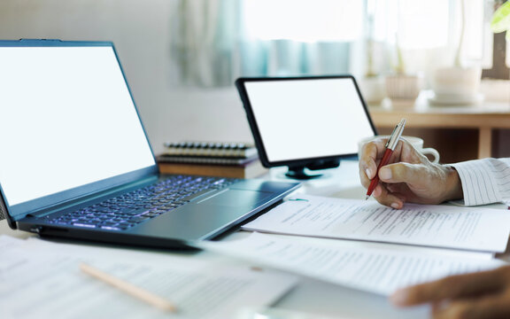close up shot, asian businessman using laptop and tablet working online checking ducuments and business contract to start new business e-commerce
