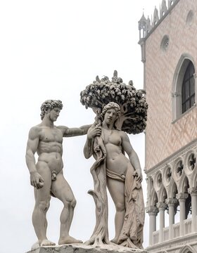 Classical marble statues of angels with trumpets in historic plaza.