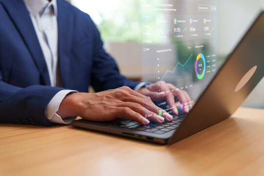 Businessman typing on a laptop with digital analytics dashboard, charts and performance metrics, representing business intelligence, data analysis, AI technology and monitoring.