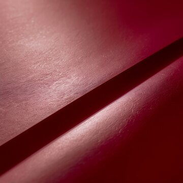 Close up of a dark red textured surface with a shadow.