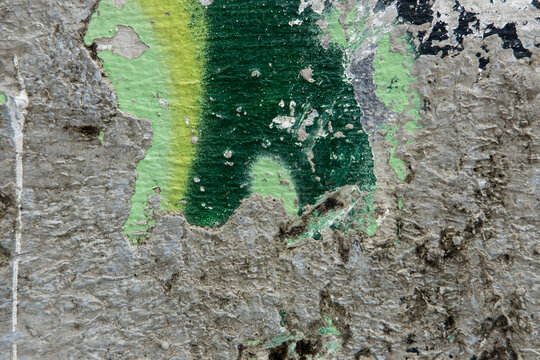 Colorful paint peeling on a textured wall showing abstract patterns in a city setting