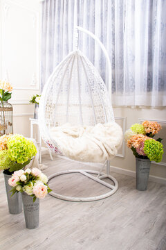 Hanging chair in a bright room with flower arrangements and natural light
