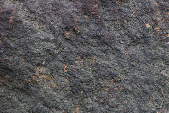 Close-up view of a rough rock surface with various textures and colors in a natural setting