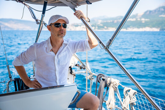 Man steering a sailing yacht on the Adriatic Sea near the Bay of Kotor in Montenegro. Freedom, sailing lifestyle and adventure travel on a private yacht.