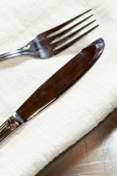 Table setting with fork and knife on linen napkin in restaurant