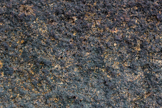 Textured rock surface showing different colors and patterns in natural light