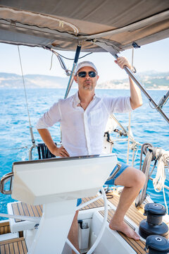 Man steering a sailing yacht on the Adriatic Sea near the Bay of Kotor in Montenegro. Freedom, sailing lifestyle and adventure travel on a private yacht.