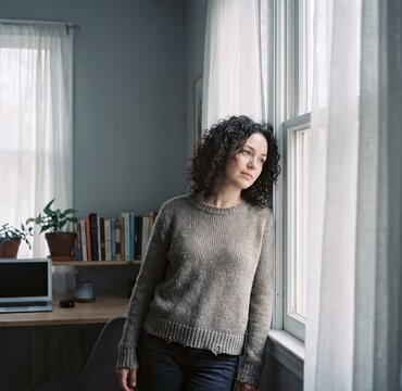 Generative AI, Pensive woman looking out window at home