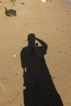 Shadow of a person standing on sandy beach during daytime