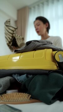 Stressed young woman struggling to pack an overfilled suitcase before a trip at home. Travel preparation luggage organization, packing stress. Vacation planning and travel anxiety concept.
