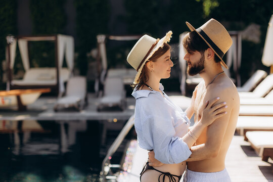 Happy couple embracing by swimming pool at resort