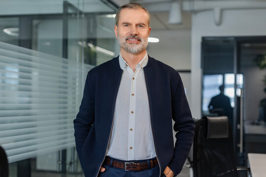 Confident stylish european man sitting at workplace, executive leader manager smiling.